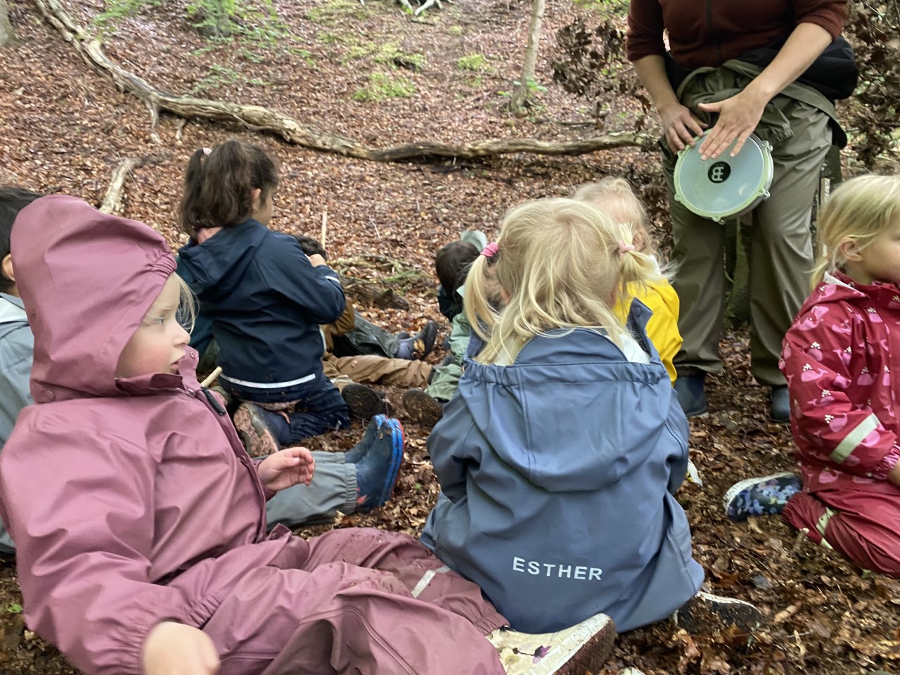 Børn hører voksen spille på tromme i skoven