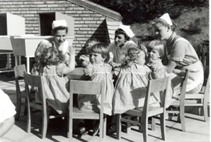 Børn ved bord sammen med barneplejersker - udendørs